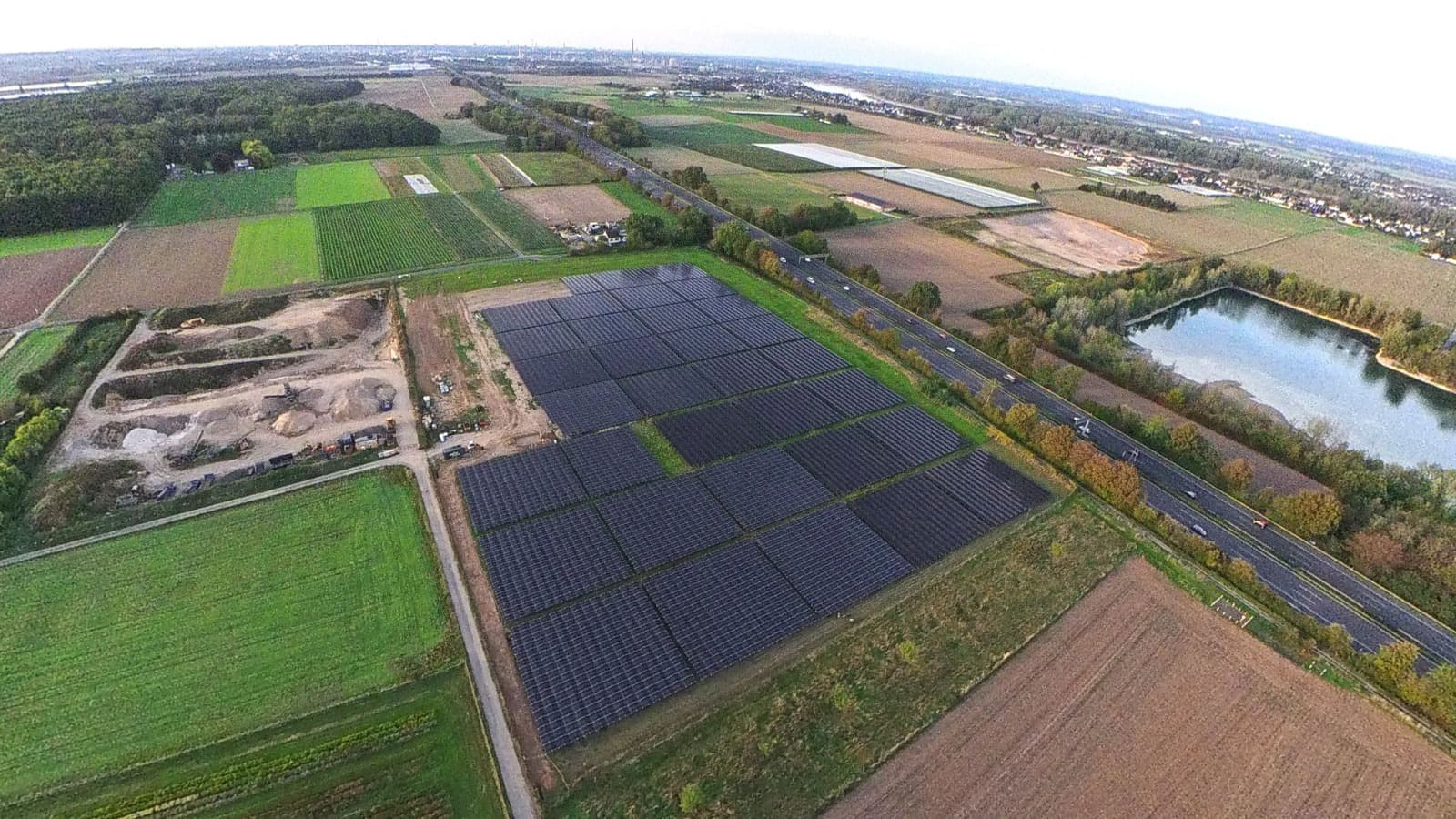 Luftaufnahme der Photovoltaik-Freiflächenanlage mit Autobahn und Baggersee im Hintergrund